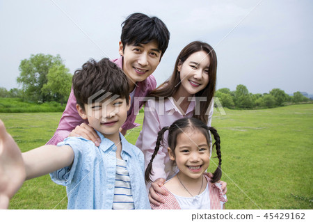 Family having picnic outdoors. Parents with two children relax in the park. Concept of happy family relations and carefree leisure time. 005 45429162