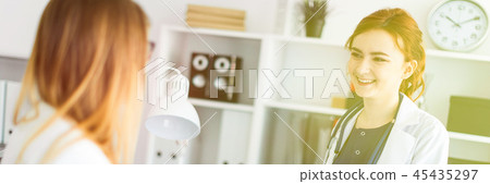 A beautiful young girl in a white robe is standing near a computer desk in the office and A beautiful young girl in a white robe is standing near a computer desk in the office and 45435297
