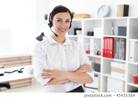 A young girl in headphones with a microphone is in a bright office. A young girl in headphones with a microphone is in a bright office. 45435389