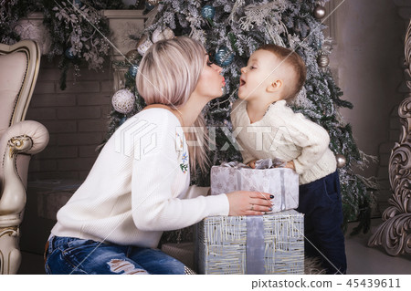 Mother and son holding present box and kissing 45439611