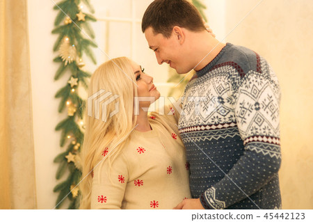 Happy couple in holiday spirit. Yong fimily in beautiful knitted sweaters in anticipation of 45442123