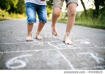 Two small boys hopscotching on a road in park on a summer day. Two small boys hopscotching on a road in park on a summer day. 45449620