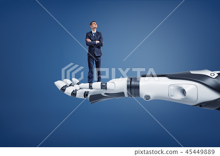 A small thinking businessman looks up while standing on a huge robotic arm. 45449889