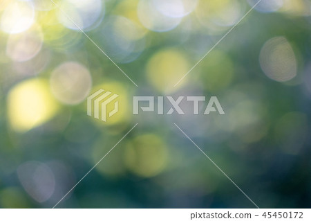 Yellow and blue bokeh circles on a blurred natural green background. Beautiful layout for your ideas 45450172
