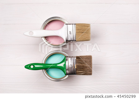 Two pink and blue open paint cans and brush on white wooden background. Two pink and blue open paint cans and brush on white wooden background. 45450299