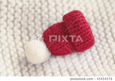 Red knitted decorative beanie with pompon on a knitted sweater 45454578