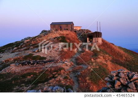 早晨的陽光和早晨的陽光在早晨的陽光下在主要的山間小屋正好在Itoyo山峰的頂峰下面 早晨的陽光和早晨的陽光在早晨的陽光下在主要的山間小屋正好在Itoyo山峰的頂峰下面 45465524