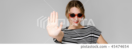 Young girl with glasses shows a hand sign stop. 45474654