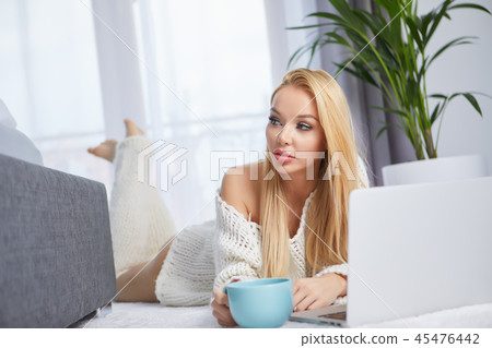 Young woman using laptop in bedroom floor 45476442