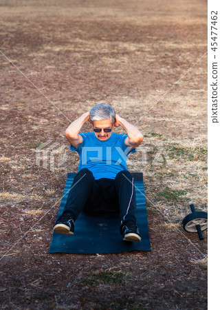 Senior doing crunches outdoors Senior doing crunches outdoors 45477462