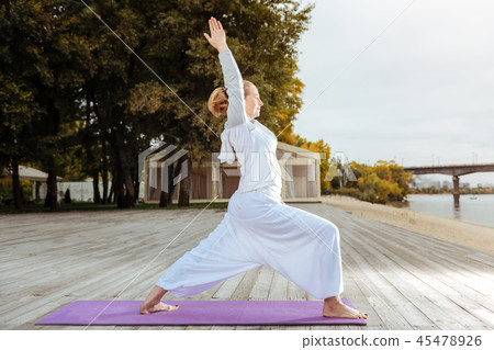 Woman in warrior pose practising yoga asanas on the beach Woman in warrior pose practising yoga asanas on the beach 45478926