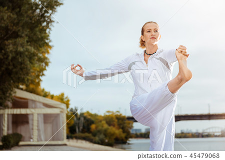 Young woman standing in the complicated pose while doing yoga Young woman standing in the complicated pose while doing yoga 45479068
