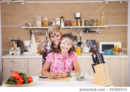 Mother and daughter joking around while they cook together Mother and daughter joking around while they cook together 45480554