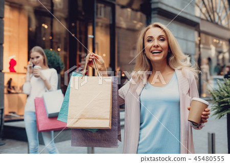Beautiful lady holding cup of coffee while her daughter talking on cellphone Beautiful lady holding cup of coffee while her daughter talking on cellphone 45480555