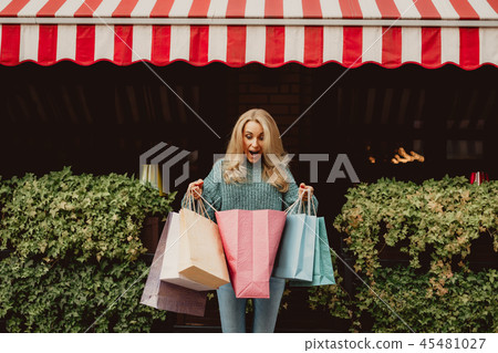 Beautiful woman looking in the shopping bag with excitement Beautiful woman looking in the shopping bag with excitement 45481027