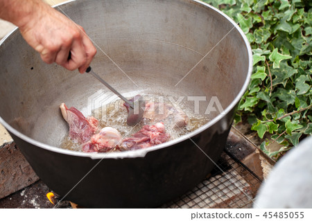 Cook mixes lamb pieces in cauldron 45485055