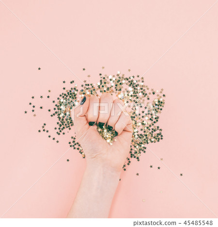 Woman hands covered golden stars confetti on pink Woman hands covered golden stars confetti on pink 45485548