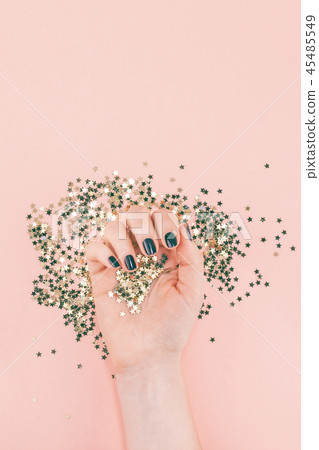 Woman hands covered golden stars confetti on pink Woman hands covered golden stars confetti on pink 45485549