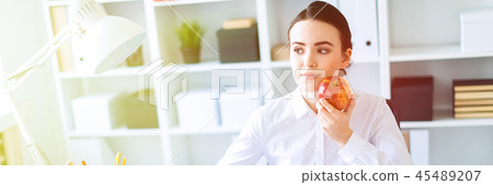 Young girl in the office working with documents and holding an apple. 45489207