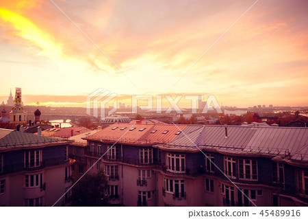 Clouds of beautiful color against the roofs of houses. Sunset pink red orange. 45489916