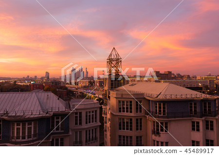 Clouds of beautiful color against the roofs of houses. Sunset pink red orange. 45489917