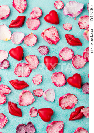 Chocolate heart and lips shaped candies with rose candied sugared petals. Blue background. Top view. Chocolate heart and lips shaped candies with rose candied sugared petals. Blue background. Top view. 45492362