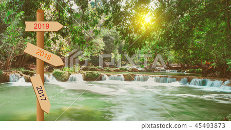 Small Waterfall in autumn forest and sign pole  45493873