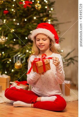 smiling girl in santa hat with christmas gift 45495729