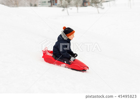 happy boy sliding on sled down snow hill in winter happy boy sliding on sled down snow hill in winter 45495823