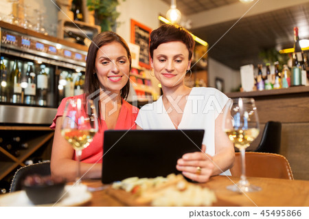 women with tablet pc at wine bar or restaurant 45495866