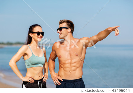 happy couple in sports clothes and shades on beach happy couple in sports clothes and shades on beach 45496044