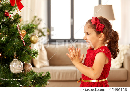 little girl decorating christmas tree at home 45496138