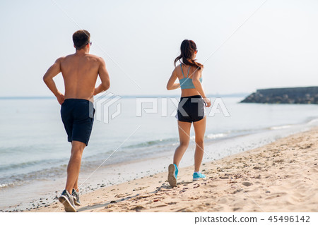 couple in sports clothes running along on beach couple in sports clothes running along on beach 45496142