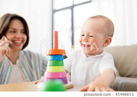 baby playing toy and mother calling on smartphone 45496653