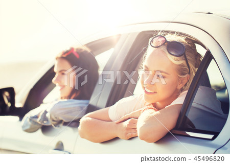 happy teenage girls or women in car at seaside 45496820