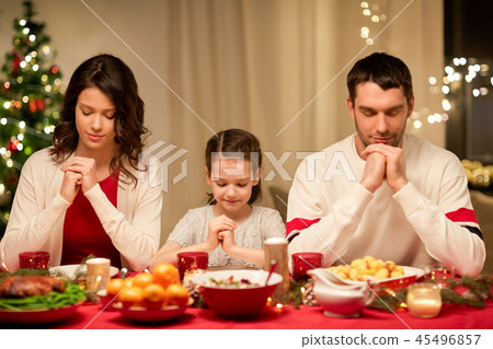 family praying before meal at christmas dinner family praying before meal at christmas dinner 45496857