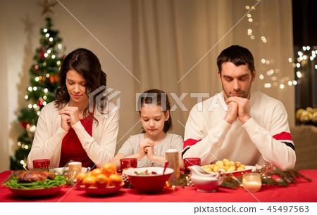 family praying before meal at christmas dinner family praying before meal at christmas dinner 45497563