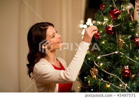 happy woman decorating christmas tree at home 45497571