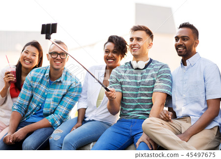 friends taking picture by on selfie stick in city 45497675