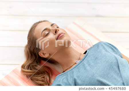 woman doing yoga corpse pose at studio 45497680