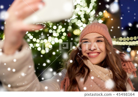 young woman taking selfie over christmas tree 45498164