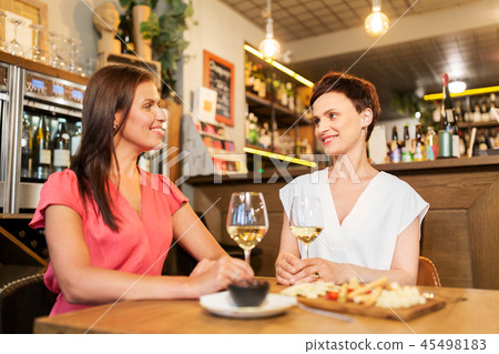 happy women drinking wine at bar or restaurant happy women drinking wine at bar or restaurant 45498183