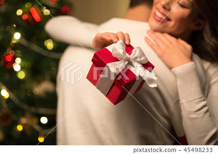 close up of couple with christmas gift hugging 45498233