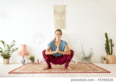 young woman doing garland pose at yoga studio 45498826