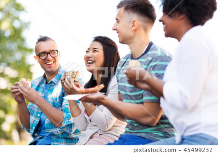 happy friends eating sandwiches and pizza outdoors happy friends eating sandwiches and pizza outdoors 45499232
