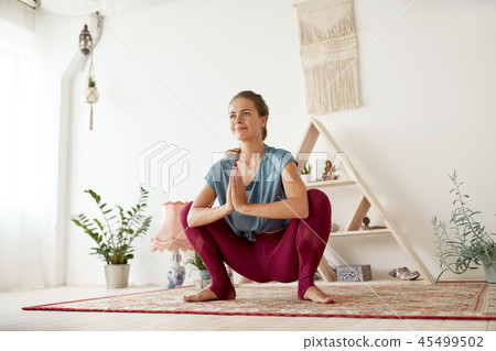 young woman doing garland pose at yoga studio 45499502