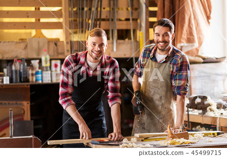 happy carpenters with drill and board at workshop 45499715