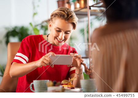 happy woman photographing cake at cafe 45499755
