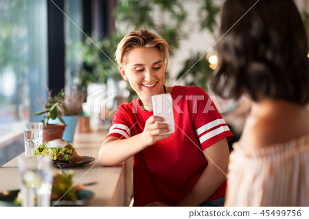 women having lunch and photographing at cafe 45499756