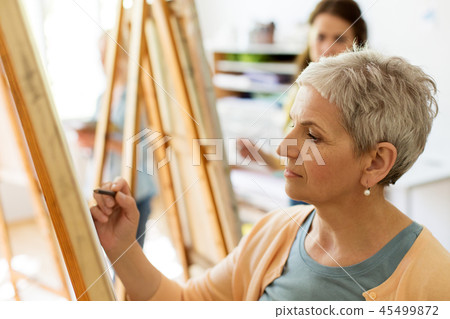 senior woman drawing on easel at art school studio senior woman drawing on easel at art school studio 45499872